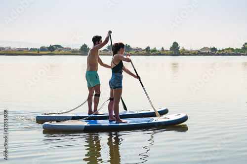 Man and woman stand up paddleboarding © homydesign