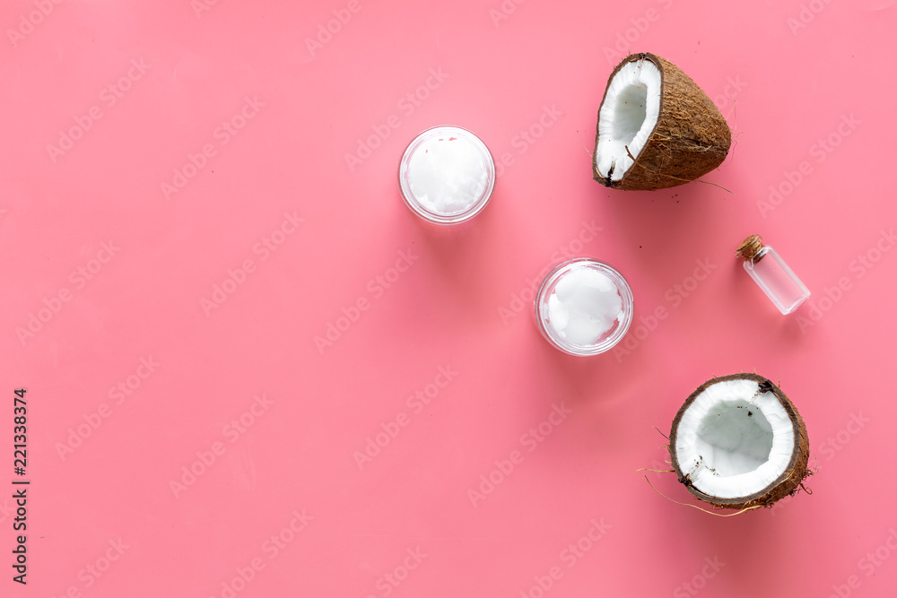 Cosmetics based on coconut oil. Oil in small bottle, cream, coconut pulp, half of coconut with shelf on pink background top view copy space Cosmetics based on coconut oil. Oil in small bottle, cream, coconut pulp, half of coconut with shelf on pink background top view copy space