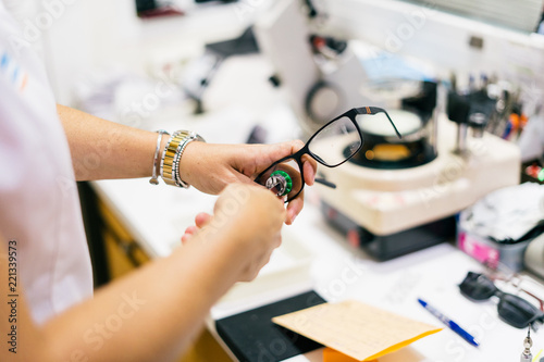 Female optician measuring and preparing glasses on the latest digital device in optical store. Professional ophthalmology instrument in clinic office and optics