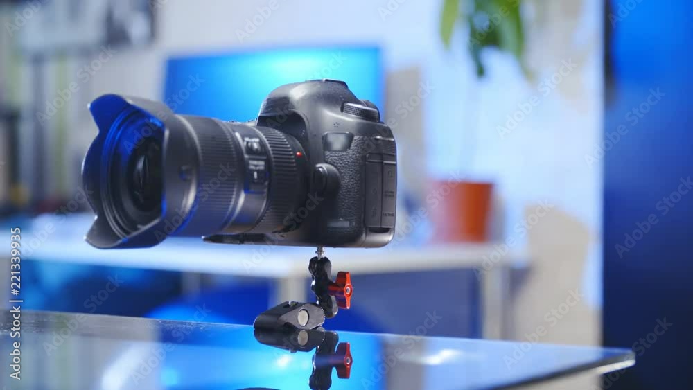 Professional camera on crab clamp attached to table edge 4K. Dolly slide shot of a camera in focus held by crab clamps to a glass table indoors. Professional camera on crab clamp attached to table edge 4K. Dolly slide shot of a camera in focus held by crab clamps to a glass table indoors.