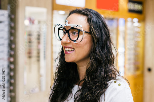 Stand with glasses in the store of optics. A woman chooses glasses. Emotions. Ophthalmology.