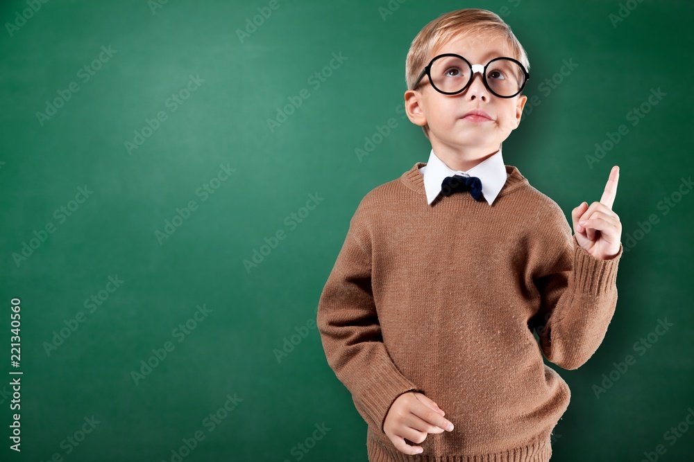 Cute little schoolgirl in glasses on blackboard background