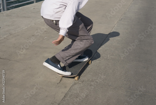 Young male skates low on a pier