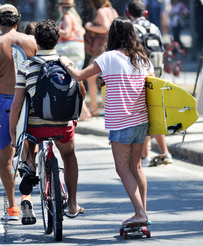 young couple with bike, surfboard and skate