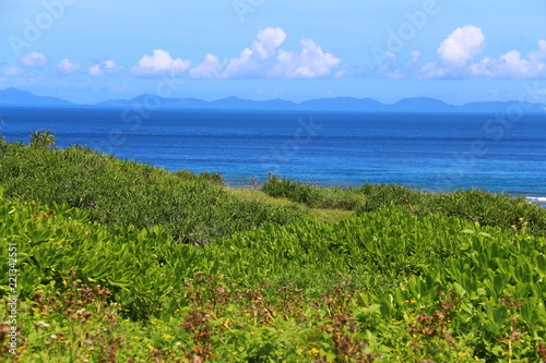 Scenic green hill with ocean and bright blue sky