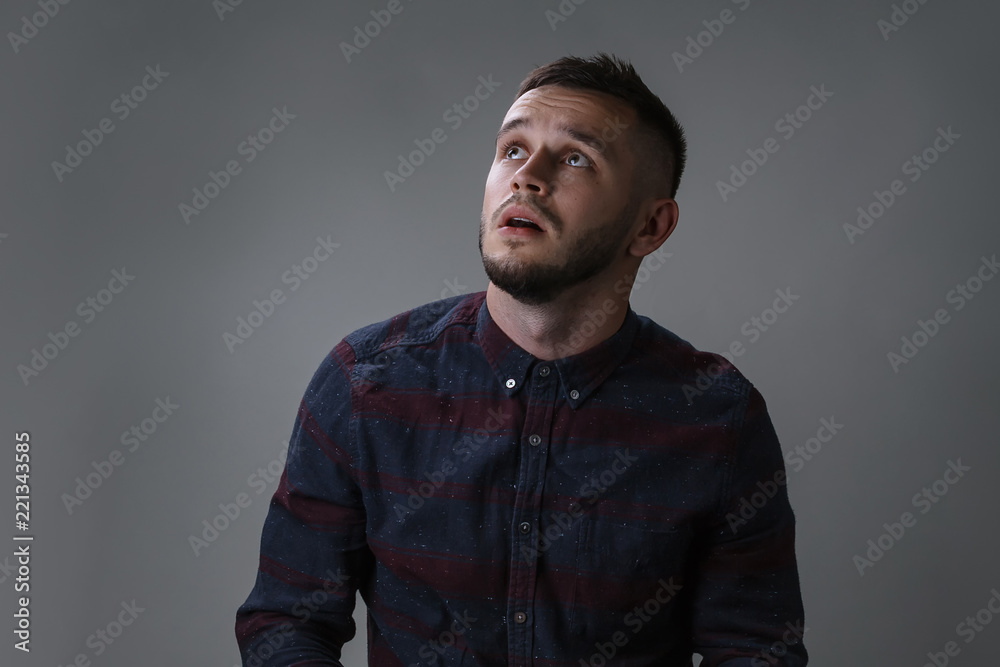 Emotion, advertisement and people concept - funny young man being amazed and surprised over gray background