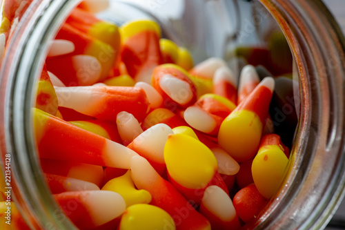 Halloween theme featuring a spilling of candy corn from a jar not a wooden table.