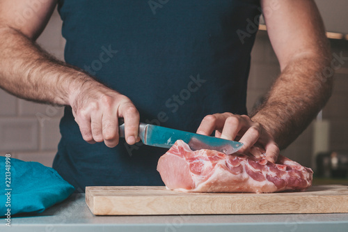 Fototapeta Naklejka Na Ścianę i Meble -  The man cuts meat - pork loin on a bone
