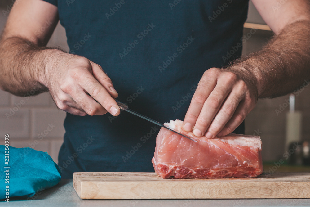 A man cooks pork in the kitchen