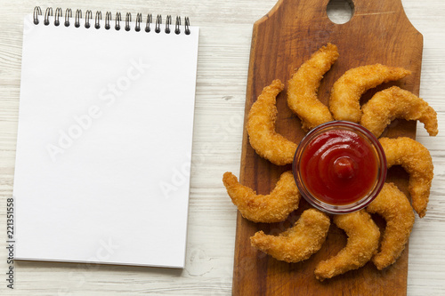 Fried shrimps tempura with sauce and blank notepad over white wooden background, top view. Space for text.
