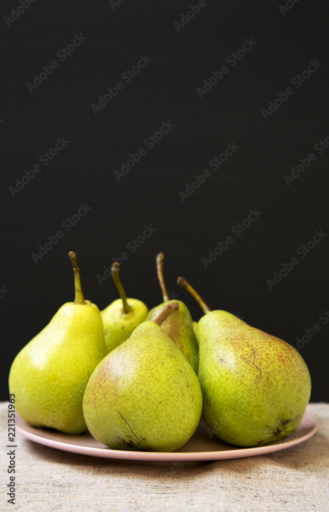 Tasty fresh pears on pink plate against black background, side view. Closeup. Selective focus. Copy space. Tasty fresh pears on pink plate against black background, side view. Closeup. Selective focus. Copy space.