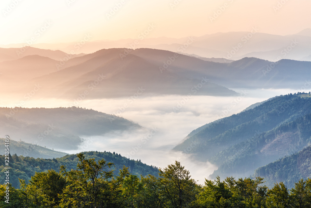 Gorgeous morning scene in high mountains. Fog soar over mountain villages. Panoramic aspect ration. Hiking or any outdoors activity background. Suitable for wallpapers on screen of digital device.