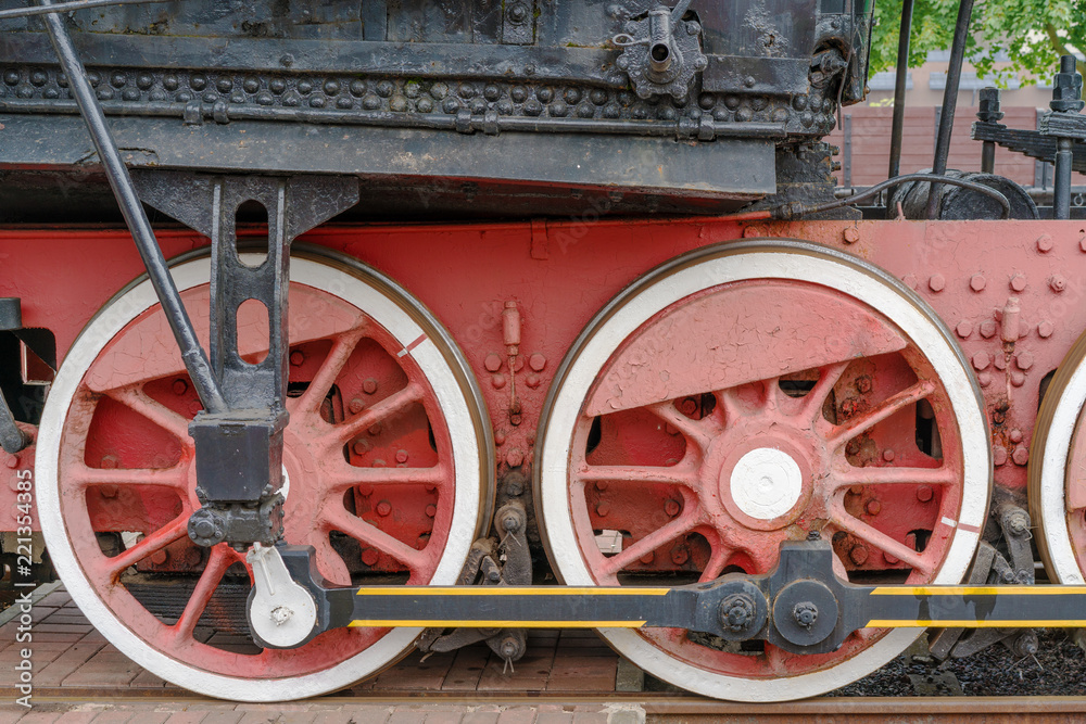 Red large iron wheels of an old vintage locomotive on railroad close-up. Wheels of a locomotive. Large wheels.