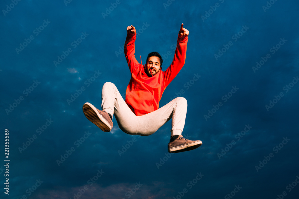 Sporty man trains parkour outdoor. Young parkour man while jumping in park on a sunrise