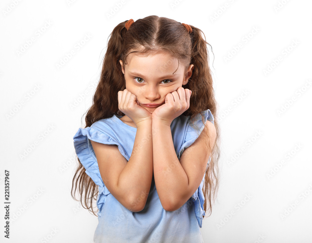 Beautiful thinking girl looking sad with hands under the face. Closeup portarit of cute kid with long hair on white background Beautiful thinking girl looking sad with hands under the face. Closeup portarit of cute kid with long hair on white background