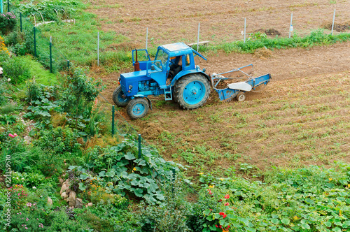 Fertilizing fields. Blue tractor fertilizing a field. Farmers spreading fertilizer with shovels.