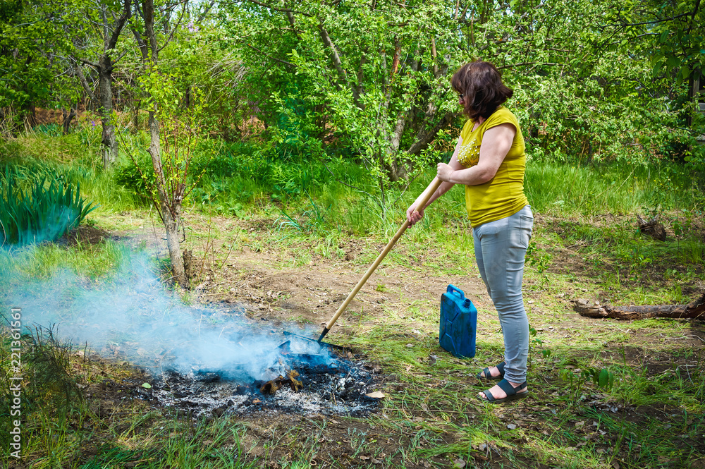 woman burns the grass in the village in the garden