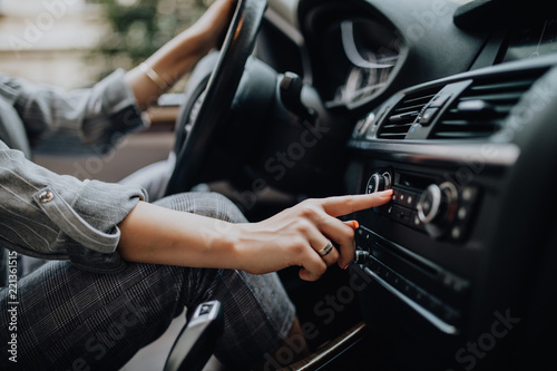 Car dashboard. Radio closeup. Woman sets up radio while driving car