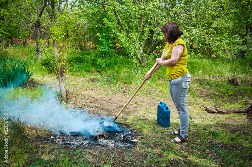 Obraz na płótnie woman burns the grass in the village in the garden w salonie