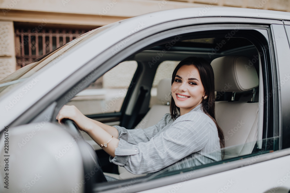 Businesswoman sitting in drivers seat in her car while driving in the street