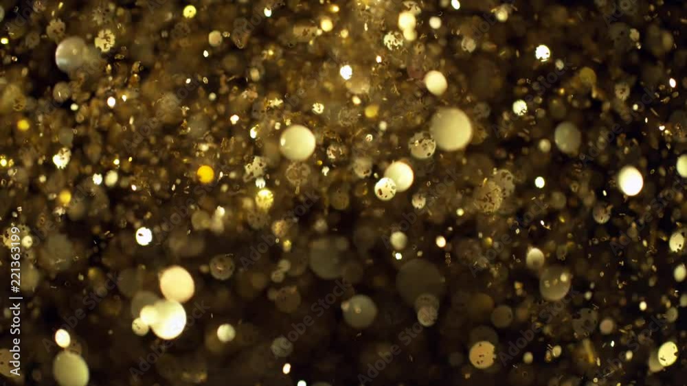 Super slow motion of glittering golden particles on black background. Shallow depth of focus. Filmed on high speed cinema camera, 1000 fps.