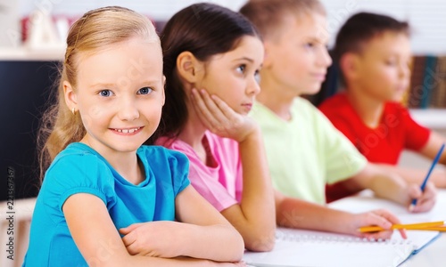 Little girl on painting lesson in school with blurred boys on