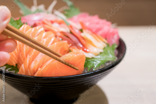 Mixed sliced fish sashimi on ice in black bowl. Sashimi Salmon Tuna Hamachi Prawn and Surf Calm set, raw fish, japanese food in Asian restaurant.