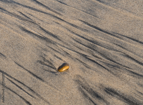 Streak like lines and a single rock on a sandy ocean beach photo