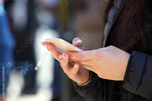 girl's hand with a smartphone and a cigarette