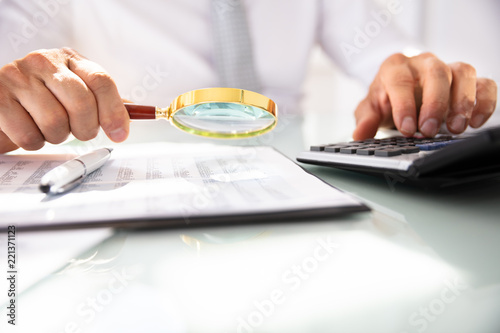 Businessman Analyzing Financial Report With Magnifying Glass