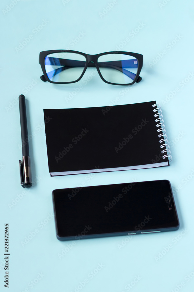Notebook with pen and and glasses on a blue background. Notebook with pen and and glasses on a blue background.