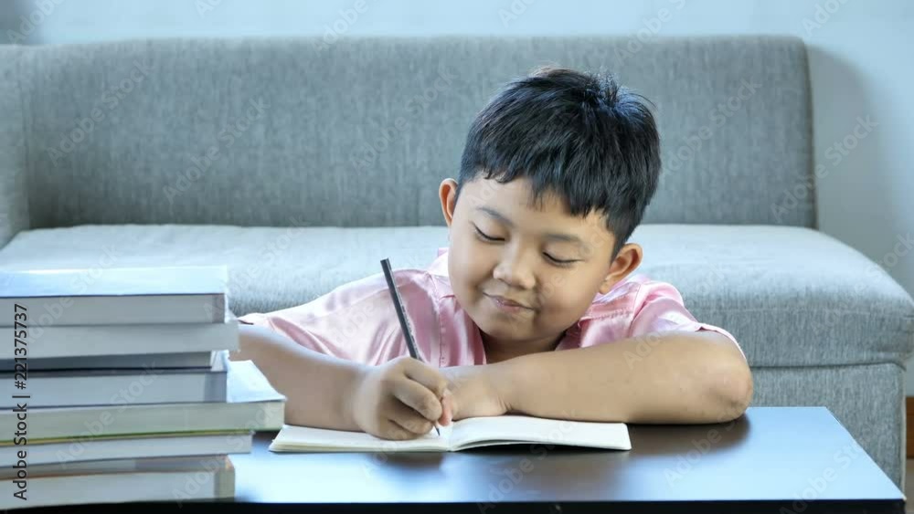 Cute little boy asian thinking and write into book, Happy smile at home. education concept Cute little boy asian thinking and write into book, Happy smile at home. education concept