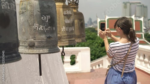 Woman taking photo with cellphone of bells in Buddhist temple
 photo