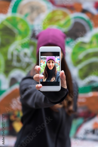 Young woman smiling and taking a selfie with her smartphone