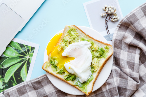 Healthy Breakfast with Bread Toast and Poached Egg with Green Avocado. Flat lay desktop with laptop