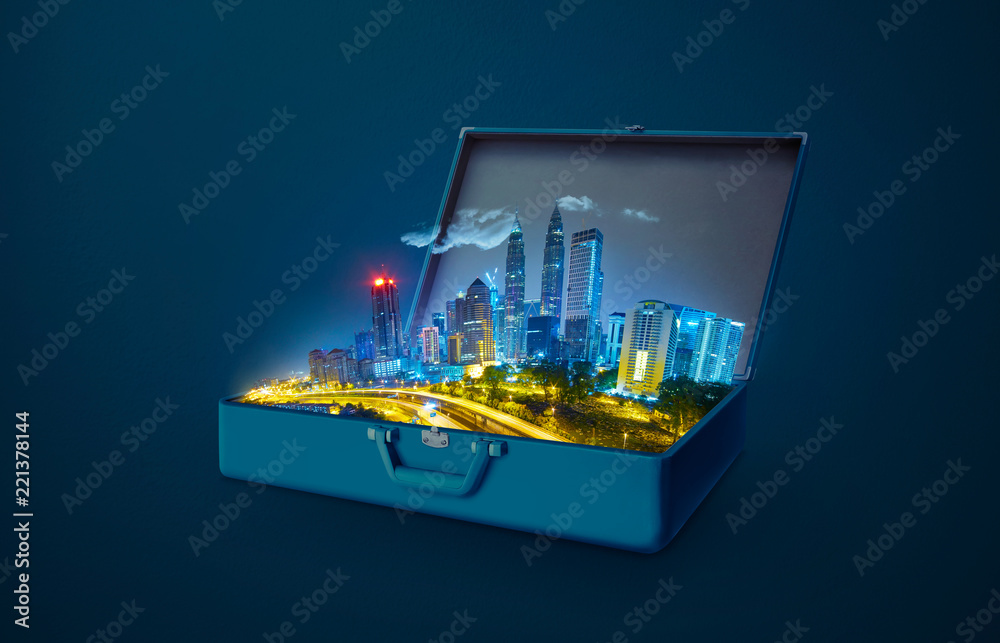 Night scene modern city skyscraper in an open retro vintage suitcase isolated on blue background .