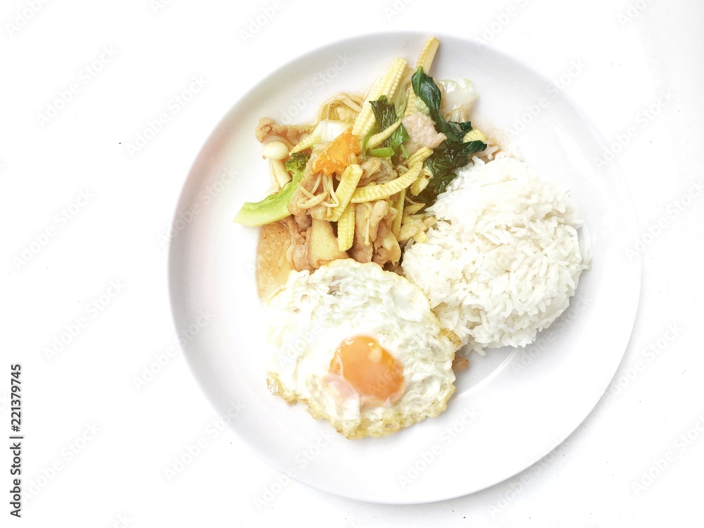 Stir fry chicken, sweet peppers, corn, broccoli, sweet basil and green beans with rice and fried egg in ธhai style in white dish on white background. Thai style food. Stir fry chicken, sweet peppers, corn, broccoli, sweet basil and green beans with rice and fried egg in ธhai style in white dish on white background. Thai style food.