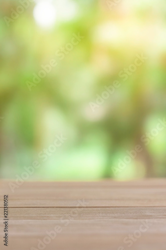 Empty wooden table with green blur light background.
