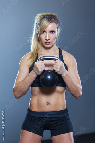 Fit woman doing squats with kettlebell in sport club. gym