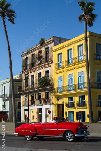 El auto antiguo de color rojo pasa entre las palmeras. © jesuschurion57