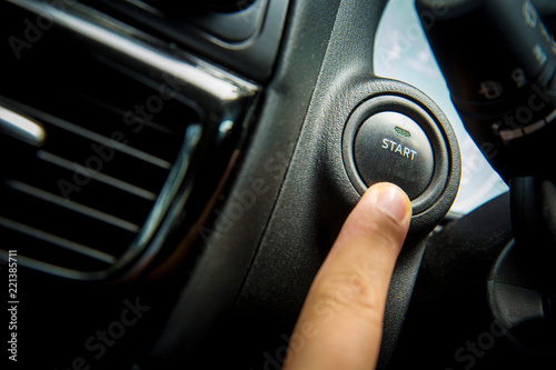 Car Push start.Closeup of hand pushing a start button of a car while steering the car.finger pressing the Engine start stop button of a car. © kanpisut