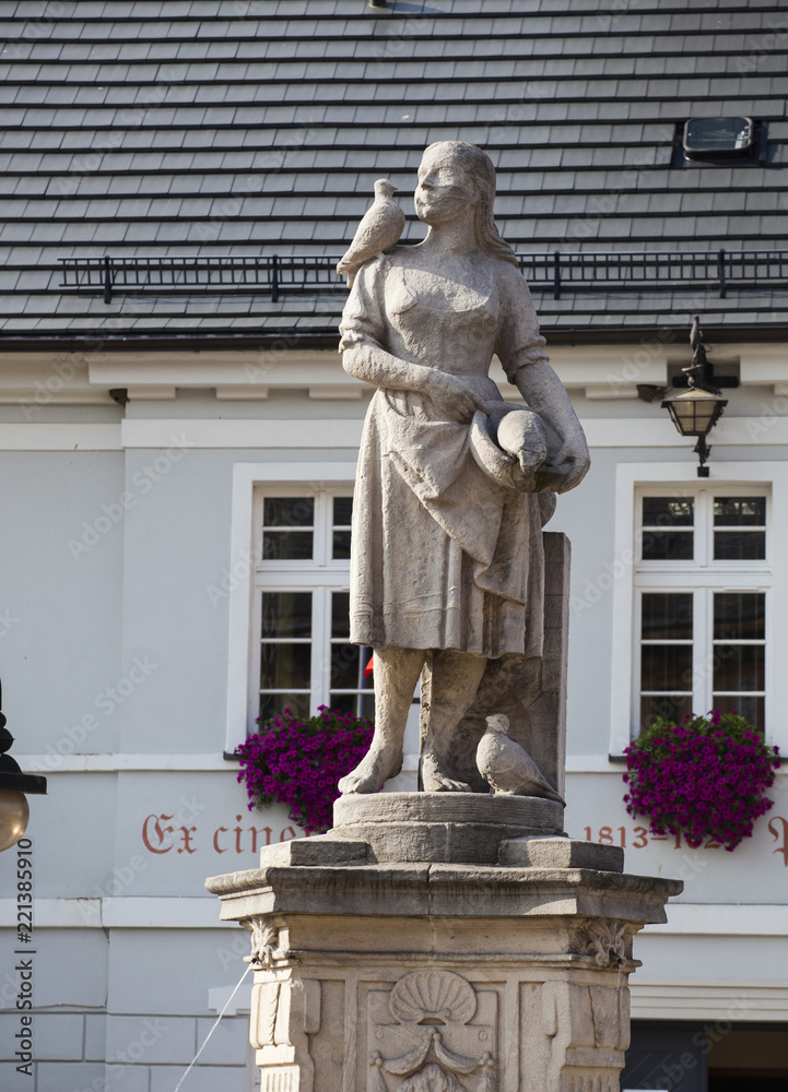Obraz premium Sculpture of a girl with pigeons near the town hall of the city on the square Bohaterow Nysy in Wlen in Poland 