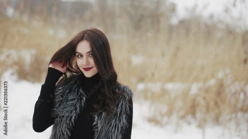 Beautiful brunette girl posing at the camera on a winter day against a background of dry reeds. Beautiful brunette girl posing at the camera on a winter day against a background of dry reeds.