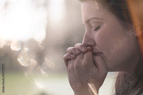 Close-up on hands and face of sad young woman with anxiety against blurred background photo