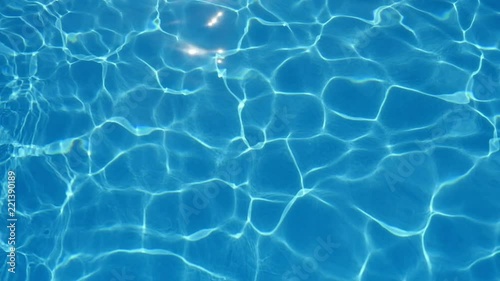 A marvelous view of swaying cyan-blue waters in a swimming pool with sparkling grid playing cheerfully in summer in slow motion