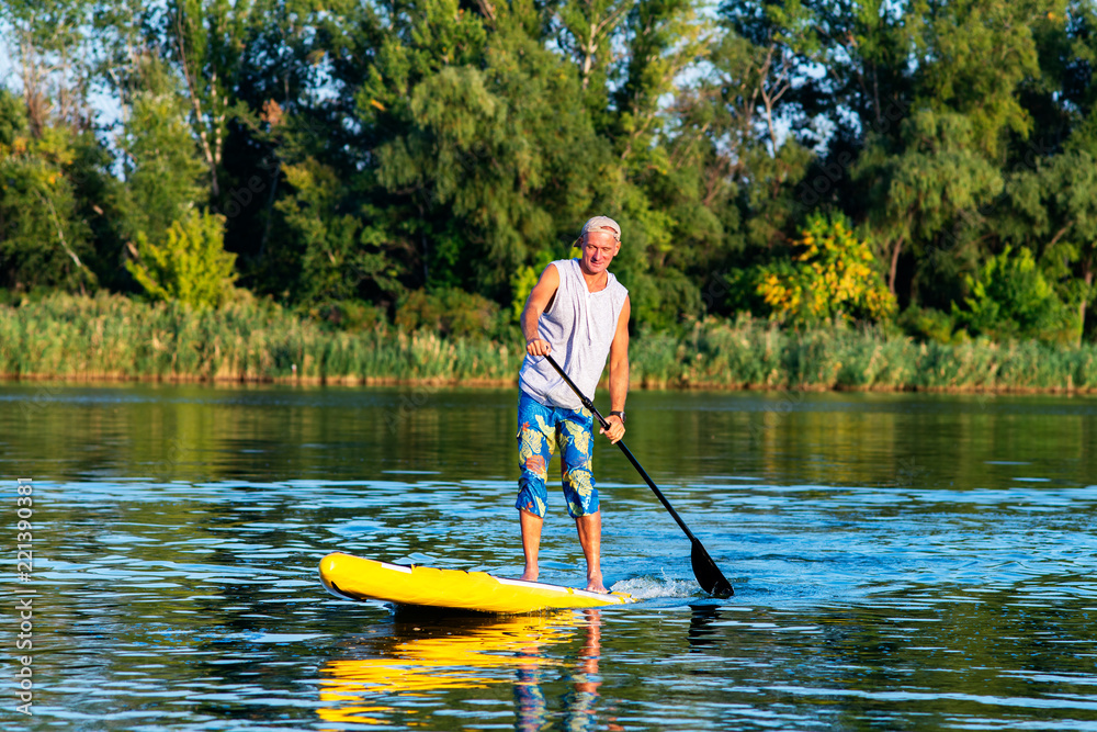 Strong man is training on a SUP board on large river