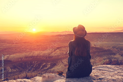 A girl in a hat on top of a hill in silence and loneliness admires a tranquil natural landscape in search of a soul. photo