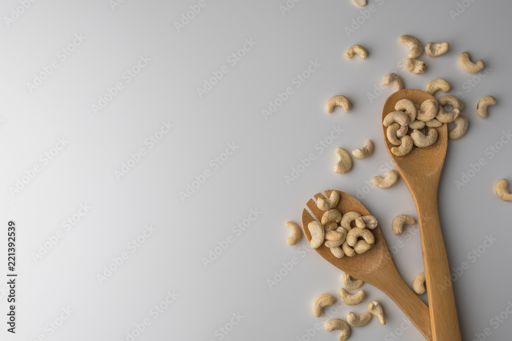 Piles of cashew in wooden spoones on white background. Nuts for health. Selective focus