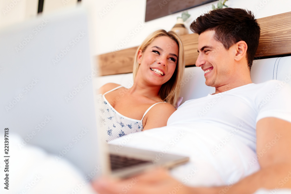 Beautiful couple using laptop in bed Beautiful couple using laptop in bed