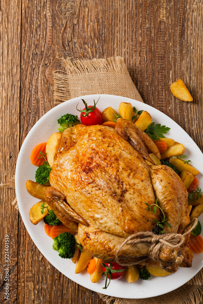 Roast chicken whole. Served on a plate with vegetables and baked potatoes. Roast chicken whole. Served on a plate with vegetables and baked potatoes.